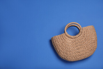 Stylish straw beach bag on blue background, top view. Space for text