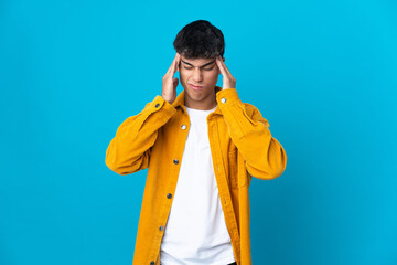 Young man over isolated blue background with headache