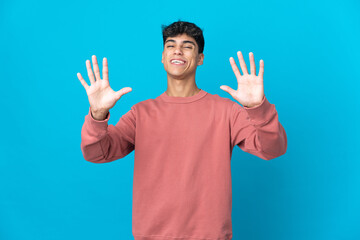 Naklejka premium Young man over isolated blue background counting ten with fingers
