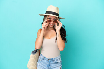 Teenager Russian girl with pamel and beach bag isolated on blue background with glasses and surprised