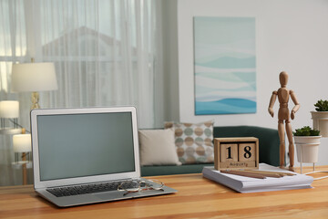 Comfortable workplace with modern laptop on wooden table in room. Interior design