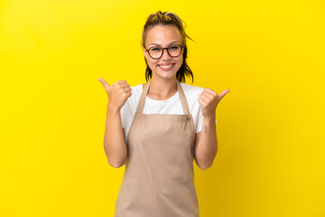 Restaurant waiter Russian girl isolated on yellow background with thumbs up gesture and smiling