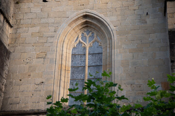 Fototapeta na wymiar Una ventana de una iglesa gotica con un arbol con hojas verdes en Hondarribia. 