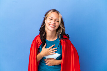 Super Hero Teenager girl isolated on blue background smiling a lot