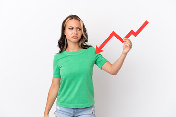 Teenager Russian girl isolated on blue background holding a downward arrow and with sad expression