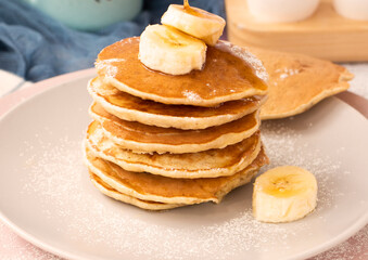 Pour maple syrup over homemade banana cupcakes. A slide of hot cupcakes with fresh bananas on a plate. Maple serop sprouts over cupcakes. Portion of breakfast on a plate. High quality photo