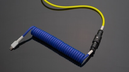 A close up image of a stylish coiled USB cable with aviator connector for keyboarr enthusiast 