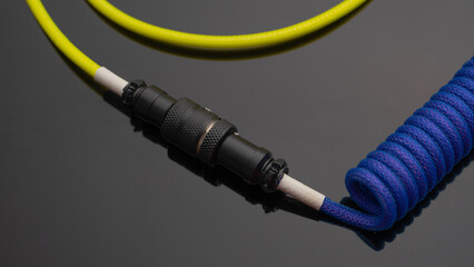 A close up image of a stylish coiled USB cable with aviator connector for keyboarr enthusiast 