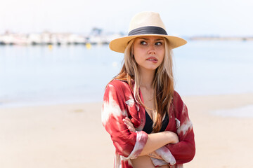 Young pretty woman in summer holidays at beach with confuse face expression