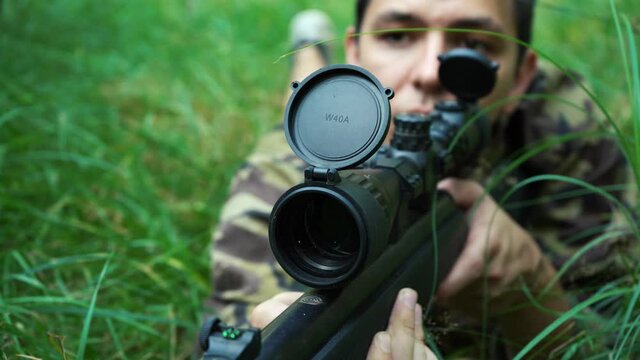 male sniper looking through the scope of his sniper rifle