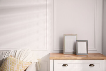 Empty photo frames on chest of drawers in living room, space for text