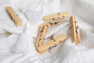 Many wooden clothespins on white garment, closeup view