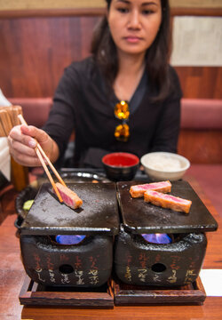 woman cooking beef katsu on traditional Japanese clay stove