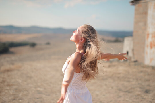 Young Woman Breathes Air With Open Arms In The Countryside