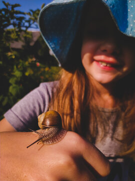 Young smiling girl with a snail on her hand close up