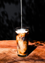 Straight on view of cream being poured into cold brew coffee