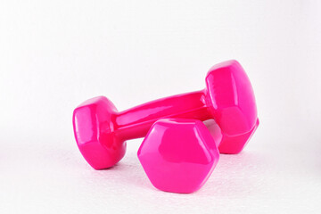 Obraz premium Two pink dumbbells on white background. Copy space.