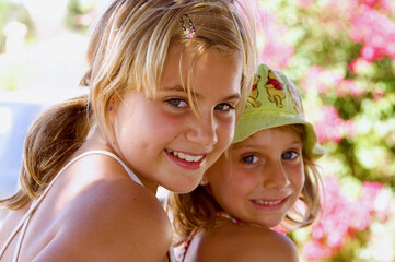 Dos niñas una con gorro verde sobre fondo de flores