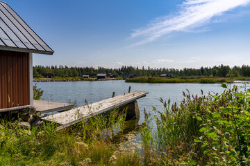 idyllic lake landscape with a wooden cottage and a wooden dock on a beautiful summer day