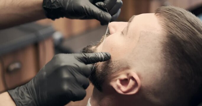 Barber doing threading procedure on face at salon