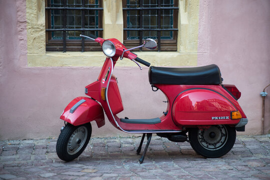 Colmar - France - 13 August 2021 - Profile view of red vespa scooter 125cc parked in the street