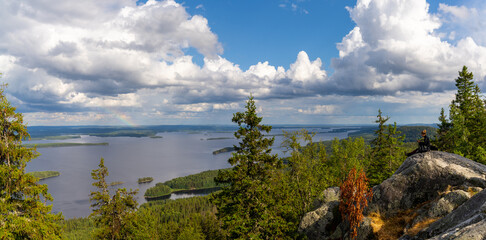 female hiker enjoys a break and the view from Koli mountain peak in the national park in Finland