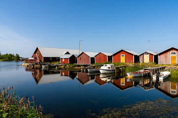 Fototapeta na wymiar colorful fishing cottages and boats reflected in the water under a blue sky