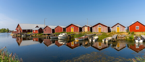 panorama view of colorful fishing cottages and boats reflected in the water under a blue sky