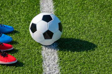 Soccer football background. Soccer ball and two pair of football sports shoes on artificial turf soccer field © vejaa