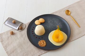 Panna cotta, traditional Italian dessert with muscat poached pears and creme Anglaise, crushed...