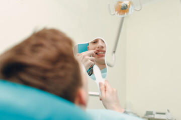 Dentistry. Dentist and patient. Dental clinic. Patient looking on smile to mirror.