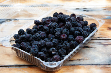 Blackberries in a transparent container on a wooden table. High quality photo