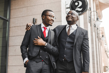Meeting of two long-time friends of black African American businessman in suits outdoors
