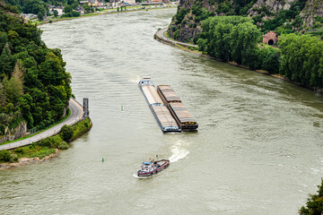Two barges with a covered deck led by a tugboat on the Rhine river in west Germany, visible road...
