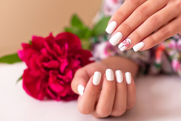 Fototapeta premium Beautiful female hands with romantic manicure nails, white gel polish, peonies flowers design
