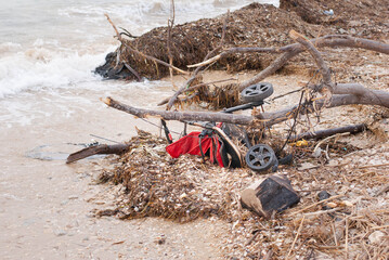 Filthy beach on the Mediterranean Sea in Israel, plastic boths, stroller, dead fish