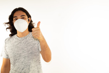 Hispanic man with long hair wearing a kn95 face mask on a white background with a thumb up