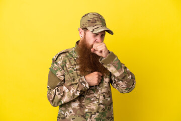 Military Redhead man over isolated on yellow background is suffering with cough and feeling bad