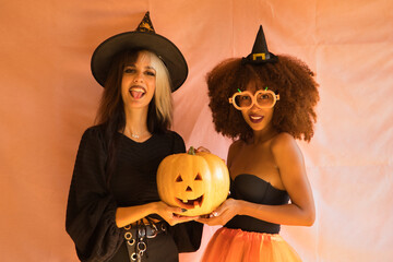 Portrait of young Hispanic and Latina women dressed as a witch smiling, sticking out a tongue and...