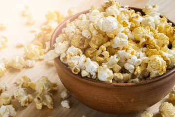 Ceramic bowl of popcorn on a wooden table top.