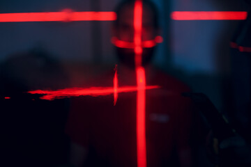 Man in dark with face illuminated by scan red laser on contour.