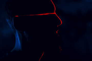 Man in dark with face illuminated by scan red laser on contour.