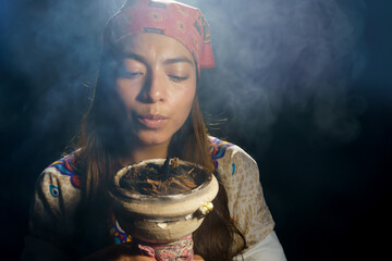 a spiritual woman holding burning tobacco and incense