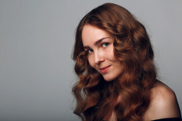 Naklejka premium Portrait of woman with wavy hair on gray background.