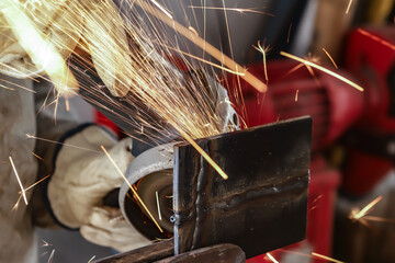 Sparks from the act of grinding a steel plate made by a worker who can only see his hands