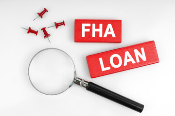 On a white background, a magnifying glass and red plates with the inscription - FHA LOAN