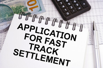 On the table there is money, a calculator and a notebook with the inscription - Application for Fast Track Settlement