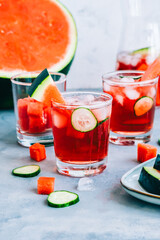 Watermelon cocktail in a glass with cucumber slice and ice cubes on the table. Refreshing drink