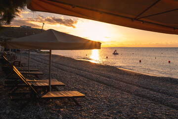 Beach umbrellas and relaxing chairs at sea at sunrise. Empty beach Pissouri Cyprus