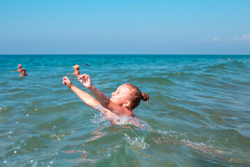 A little girl swims and has fun in the sea. Happy weekend, summer vacation.